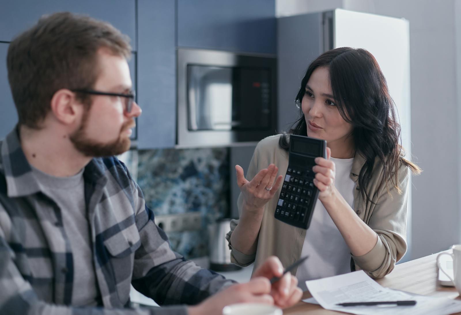 Woman Sitting at Table Holding a Calculator